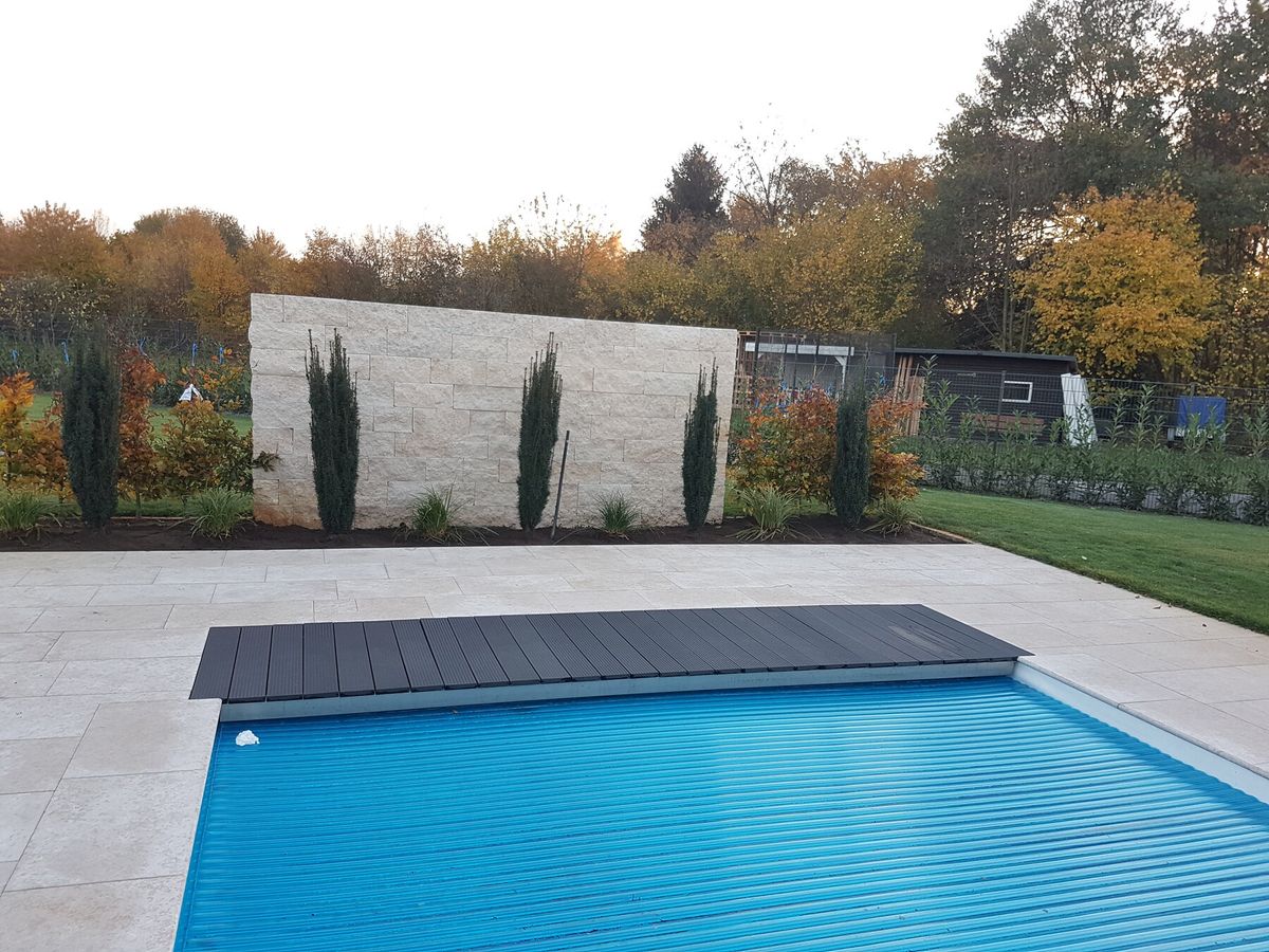 Elektrische Poolabdeckung vor der Natursteinmauer