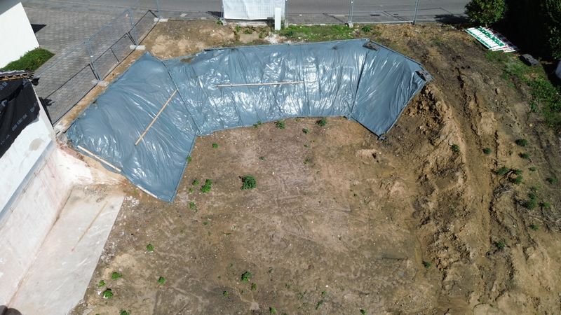 Mit Folie abgedeckte Fundamentwand entlang der Aushubfläche, aus der Luft