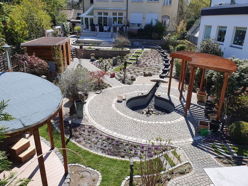 Pflasterrondell mit Wasserbecken und geschwungener Holzpergola
